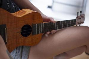 The girl plays on the ukulele. Lesson playing the guitar. photo