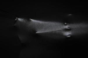 cara humana gritando y mano presionando a través de tela negra con brillo y lado oscuro para el concepto de fondo de halloween. foto