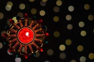 Selective focus on candle of diya lamp lit on dark background with bokeh lights. Diwali festival concept. photo