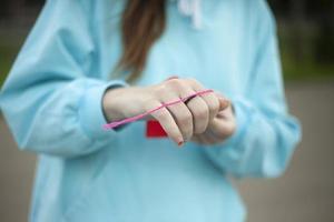 Child ties thread to heart. Girl holds red cardboard in her hands. Needlework on street. photo