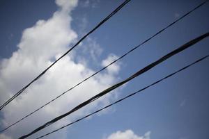 Wires against the sky. City communications. Black plastic insulated electrical wires. Lots of lines tangled together. photo