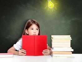 Young cute girl at chalkboard with light bulb over head photo