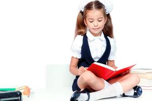 linda jovencita sentada en la mesa y leyendo un libro foto