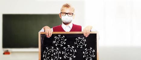 Young boy with protection mask against corona virus at school. photo