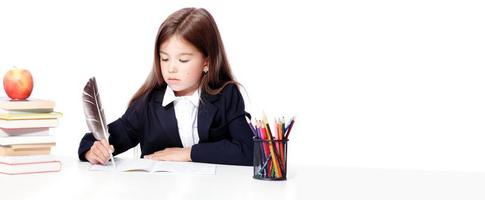 Happy and cute teen school girl writes in a book or notebook photo