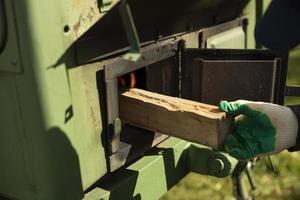 A man puts firewood in the stove. Burning a wooden bar in an outdoor kitchen. photo