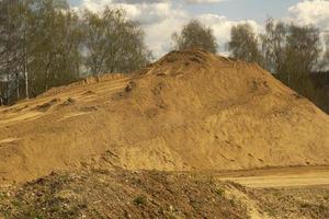 Mountain of sand. Embankment for the construction of the route. Sand on the road. photo