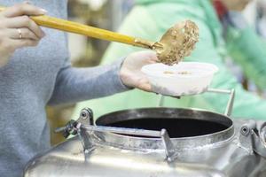 The girl puts the porridge in a ladle in a plate. A hot food container. photo