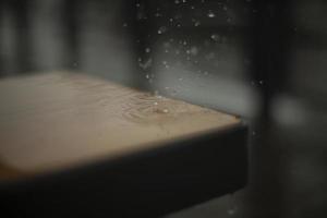 Raindrops break on the surface of the bench. Rain outside in detail. photo
