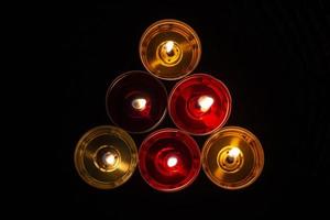 The candles are laid out in a triangle. Candles burn in the dark. Red and yellow wax. photo