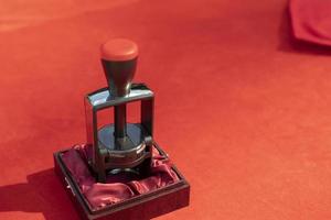 Seal for solemn signing by document. A red tablecloth on the table and an item for stamping envelopes. The predominance of red. photo