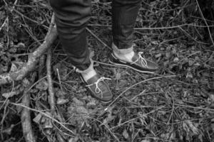 pies del hombre con botas auténticas y vaqueros de orillo, en el fondo de las ramas foto