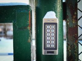 Password code security keypad system number combination to unlock the green iron gates outside the house in winter snow photo