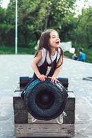 preschool girl sitting on top of a cannon photo