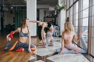 mujeres atractivas jóvenes practicando yoga cerca de la ventana foto