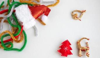 composición navideña. oropel, árbol de navidad rojo, juguetes de paja sobre un fondo blanco. el concepto de navidad, invierno, año nuevo. diseño plano, vista superior, espacio de copia foto