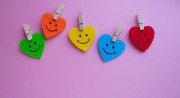 Bright hearts with smiles and small clothespins on a pink background. At the bottom is a place for your text photo