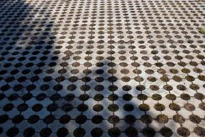 Geometric gray concrete tile with eco-parking cells With a hole for grass. Top view, paving stones for grass, block tiles made of concrete in the form of connected circles photo