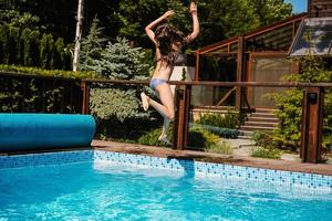 niña feliz saltando en la piscina foto