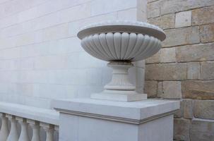 Plaster vase on a pedestal on a decorative background. Decorative element of architecture, close-up photo