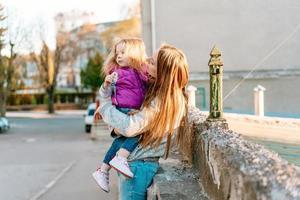 madre sostiene a una pequeña hija en sus brazos foto