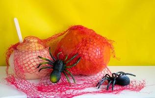 A clay pot with a wooden spoon, a pumpkin and two spiders with a red web on a white background.Halloween and Thanksgiving Day Concept photo