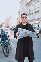 Smart man in sunglasses with paper on street photo