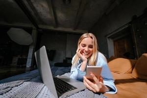 Smiling attractive woman lying on bed talking by smartphone photo