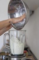 mujer vertiendo requesón en una licuadora en la cocina foto