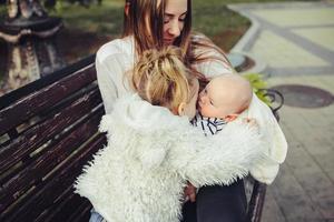 mother and two daughters rest on a bench photo