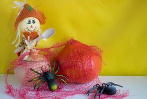 A scarecrow with a wooden spoon, a clay pot, a pumpkin and two spiders with a red web on a white background.Halloween and Thanksgiving Day Concept photo