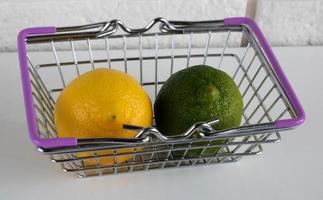 lima y limón en una cesta de la compra sobre un fondo blanco. alimentación saludable. dieta de frutas. el concepto de pérdida de peso. vista superior foto