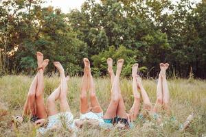 Six girls lie on the grass and raise their legs up photo