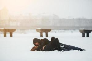 chica y chico yacen en la nieve foto