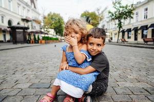 little boy and girl are sitting on the street photo