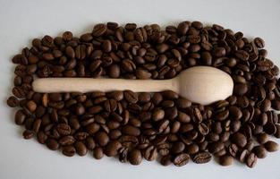 granos de café aromáticos en una cuchara de madera, para la producción de un delicioso café. granos de café tostados enteros para moler foto