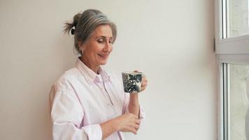 Woman drinks tea from a mug and talks to camera video