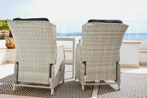 two white rattan chairs on a balcony on a sunny day photo
