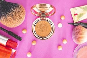 flatlay de maquillaje y productos de belleza sobre un fondo rosa. foto
