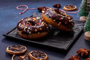 Pastries concept. Donuts with chocolate glaze with sprinkles, on a dark concrete table photo