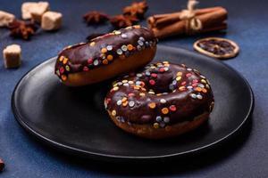 Pastries concept. Donuts with chocolate glaze with sprinkles, on a dark concrete table photo