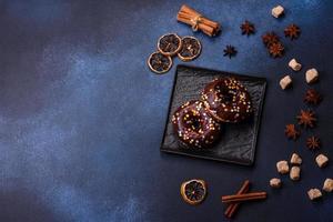 Pastries concept. Donuts with chocolate glaze with sprinkles, on a dark concrete table photo