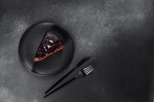 A piece of fresh delicious cake with nuts and chocolate on a black plate photo