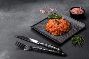 arroz hervido con pimientos, especias, hierbas y salsa de tomate en un plato de pizarra negra
