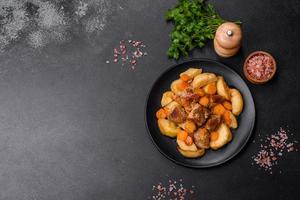 Beef meat and vegetables stew on a black plate with roasted potatoes photo