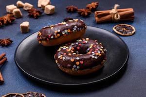 Pastries concept. Donuts with chocolate glaze with sprinkles, on a dark concrete table photo