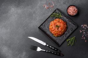 Boiled rice with peppers, spices, herbs and tomato sauce on a black slate plate photo
