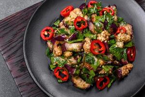 A salad of baked aubergine, sweet pepper, garlic, zucchini and parsley in a black plate photo