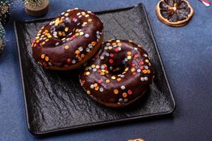 Pastries concept. Donuts with chocolate glaze with sprinkles, on a dark concrete table photo