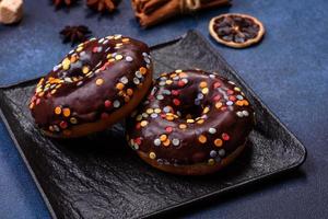 Pastries concept. Donuts with chocolate glaze with sprinkles, on a dark concrete table photo